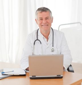 starszy lekarz przed laptopem